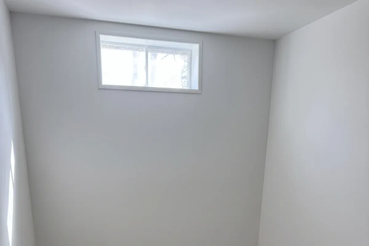Finished basement room with a daylight window and vinyl plank floor, Innov Builders project in Ashland, MA
