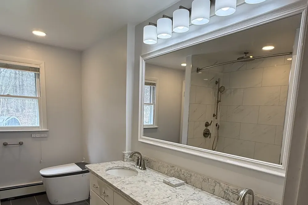 Recessed tile niche and built-in storage in a small Massachusetts bathroom by Innov Builders