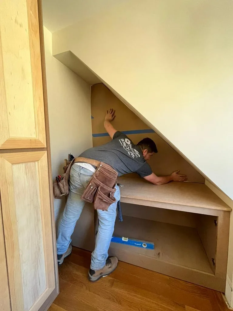 Carpenter installing custom built-in cabinetry and shelving in a Wakefield MA home — Innov Builders finish carpentry