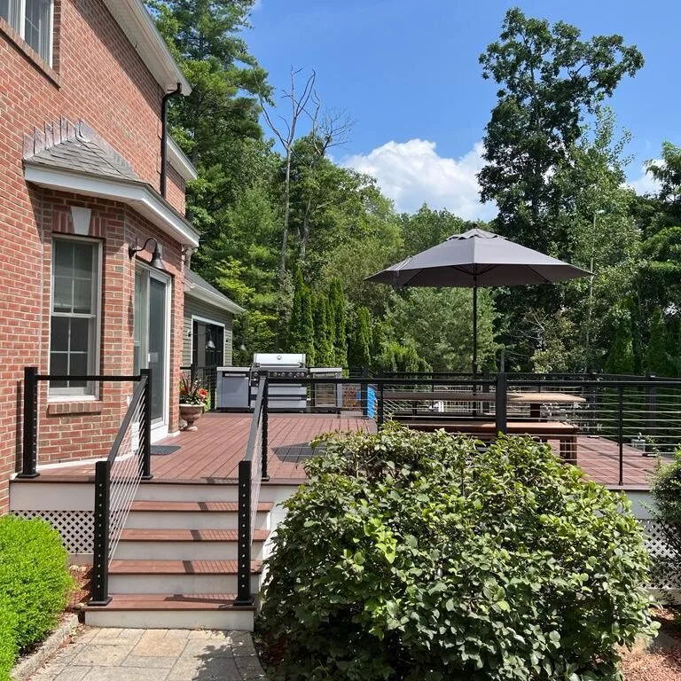 Outdoor living deck with cable railing, grill and umbrella by Innov Builders